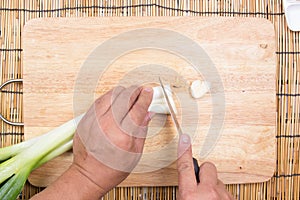 Chef cutting scallion on wooden broad