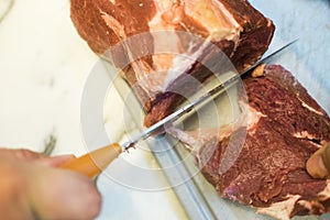 Chef cutting a slender piece of beef tenderloin with the background in blur