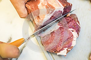 Chef cutting a slender piece of beef tenderloin with the background in blur