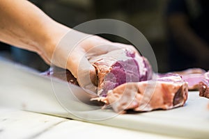 Chef cutting a slender piece of beef tenderloin with the background in blur