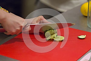 Chef cutting some lime slices to prepare a cocktail 