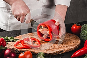 Chef cutting vegetables with knife on kitchen, cooking food. Ingredients on table.