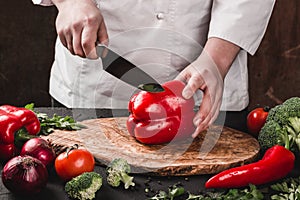 Chef cutting vegetables with knife on kitchen, cooking food. Ingredients on table.