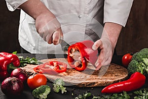 Chef cutting vegetables with knife on kitchen, cooking food. Ingredients on table.