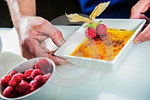 Chef decorating sweets at kitchen. Closeup male chef making dessert in motion. Professional cook decorating cake at workplace