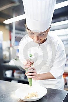 Chef, dessert and plating with professional kitchen, cooking and hospitality industry employee. Woman, catering and