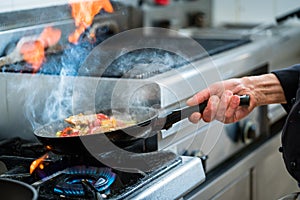 Chef doing flambe to food in pan with alcohol photo