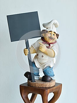 Chef doll holding signs on wall background