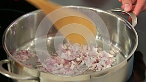 Chef drops chopped onions into pan