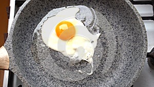 Chef egg in a frying pan over an gas burning stove