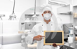 Chef in face mask with chalkboard at kitchen