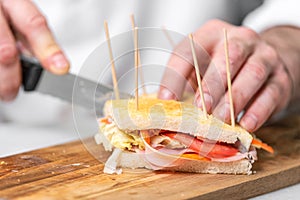 Chef finalizes the sandwich with ham and salad on the wooden board. photo
