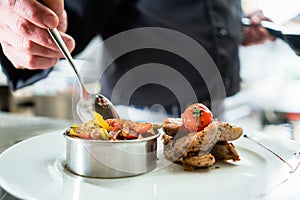 Chef finishing food on plate in restaurant kitchen