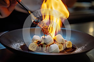 Chef flambÃÂ©ing bananas and marshmallows in a pan, creating a stunning fire display photo