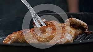 The chef flips the grilled chicken with a large fork