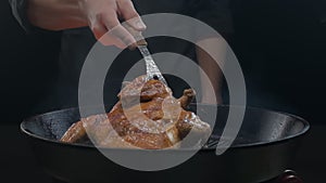 The chef flips the grilled chicken with a large fork