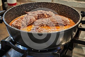 Chef fries meat rolls in a frying pan on a gas stove. French gourmet cuisine