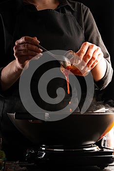 Chef fry meat in a pan, saturating tomato sauce, freezing in motion. Against the background of vegetables. Culinary recipes, tasty