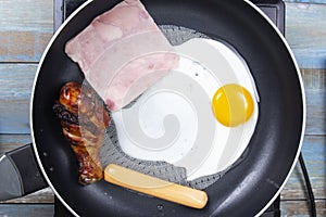 Chef frying egg ,ham,sausage and chicken drumstick in the pan