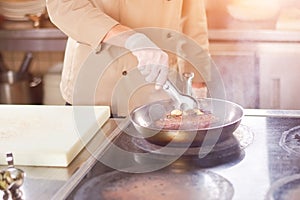 Chef frying meat with garlic.