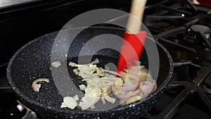 Chef frying white onion in pan.