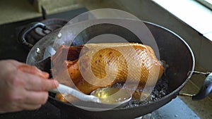 Chef frying a whole duck in a pan in the kitchen