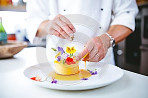 chef garnishing flan with edible flowers in the kitchen