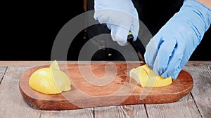 Chef in gloves slicing lemon on wooden cutting board. Restaurant food cooing. Slow motion. hd