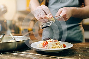 Chef grates cheese to the plate with fresh pasta