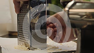 The chef grates the parmesan on a grater