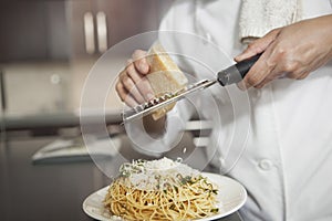 Chef Grating Cheese Onto Pasta In Kitchen photo