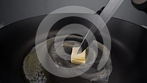 Chef greases the hot pan with butter, melting butter on the pan, butter on the end of the knife, cooking with milk