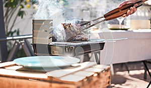 Chef grill t-bone steak at barbecue sunday lunch outdoor - Man cooking meat for a family bbq meal outside in backyard garden -