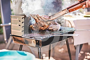 Chef grill t-bone steaks at barbecue dinner outdoor - Man cooking meat for a family bbq meal outside in backyard garden - Summe