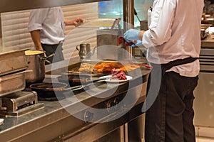 The chef preparing beef meat in barbecue restaurant`s kitchen