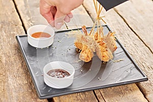 Chef hand adding sesame to fried shrimps.