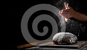 Chef hand clap with splash of white flour and black background with copy space. woman`s hands Making bread