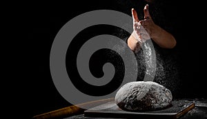 Chef hand clap with splash of white flour and black background with copy space. woman`s hands Making bread