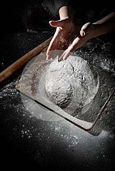 Chef hand clap with splash of white flour and black background with copy space. woman`s hands Making bread