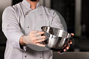Chef hand keep bowl. Closeup chef hands demonstrate steel bowl.
