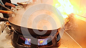 Chef handling the wok and stirring the food in restaurant kitchen