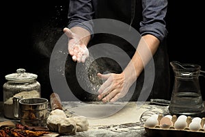 Chef hands are clapping wheat flour under rolled dough