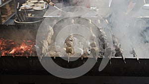 Chef hands cooking roasted meat barbecue with lots of smoke. Grilled shish kebab on metal skewer