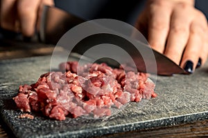 Chef hands cut red meat on a board