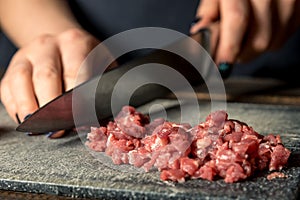 Chef hands cut red meat on a board