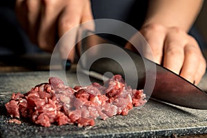 Chef hands cut red meat on a board