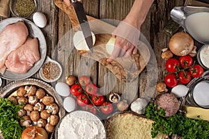 Chef hands cuts with knife onion on chopped board for meat pie on wooden table with variety of ingredients background. Concept of
