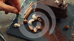 Chef hands decorating chocolate cake with fresh mint leaves in slow motion.