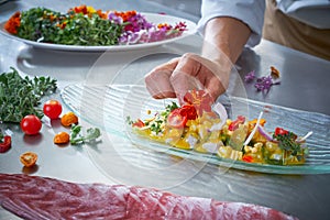 Chef hands garnishing flower in ceviche dish