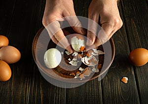 Chef hands peeling eggs on the kitchen table. Close-up of male hands peeling a boiled egg from its shell